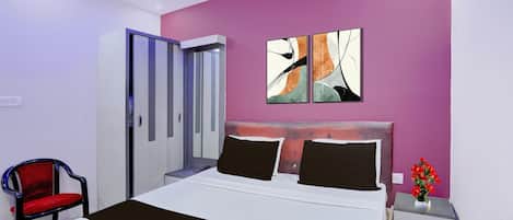 A modern bedroom with a bed, a chair, a nightstand, and abstract wall art.