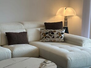 Ein Ecksofa mit zwei Kissen, einer Lampe und einem Marmortisch.