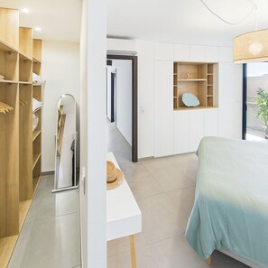 Ein Schlafzimmer mit einem Bett, einem Kleiderschrank, einem Spiegel und einer kleinen Ablagefläche mit Dekoration.