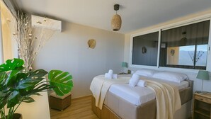 Ein Hotelzimmer mit einem Bett, Nachttischen, einem Fenster und einer großen Pflanze.