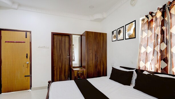 A bedroom with a bed, wooden wardrobe, a small desk, and a mirror. - Hotel O Oragadam Industrial Estates Chennai (Walajabad)
