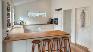 A modern kitchen with a wooden island, white cabinetry, and bar stools. - 4 bedroom lovely home in Malling (Malling)