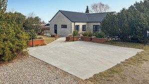 A modern building with a concrete driveway, surrounded by landscaped areas and trees. - 4 bedroom lovely home in Malling (Malling)
