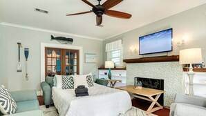 A bedroom with a bed, a ceiling fan, a television, a fireplace, and a view of the ocean. - Charmed Lagoon (Galveston)