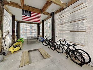 Ein Zimmer mit Tischtennisplatte, Fahrrädern, einem Kanu und einer amerikanischen Flagge.