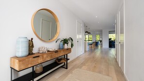 A modern hallway with a wooden console table, a large mirror, and a potted plant. - Bideawee | Coastal Luxe with Pool and Spa (Mount Martha)