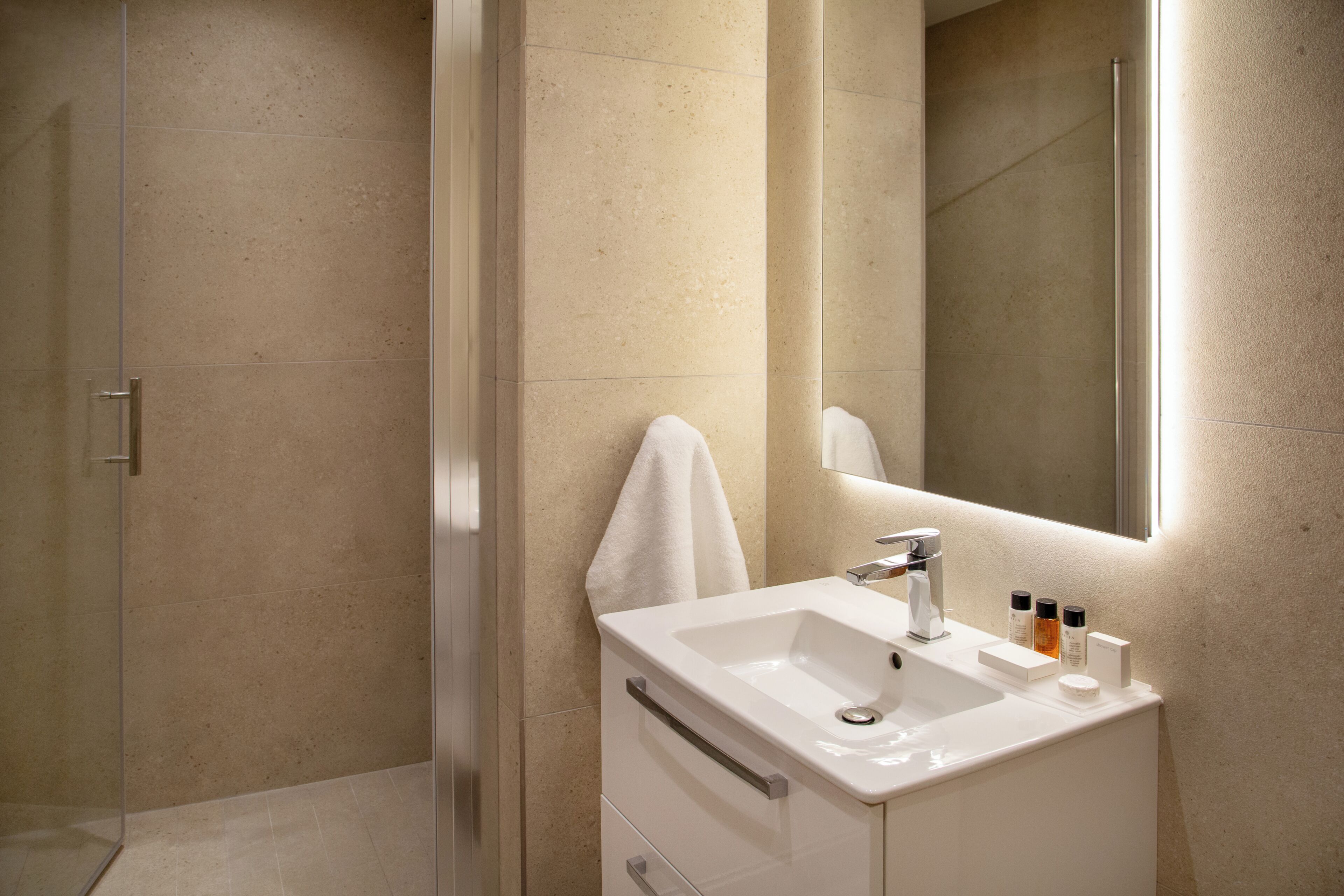 Une salle de bain moderne avec une douche en verre, un lavabo blanc et un miroir.