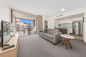 Eine moderne Wohnung mit Wohnzimmer, Essbereich, Küche und einem Balkon mit Blick auf die Stadt.