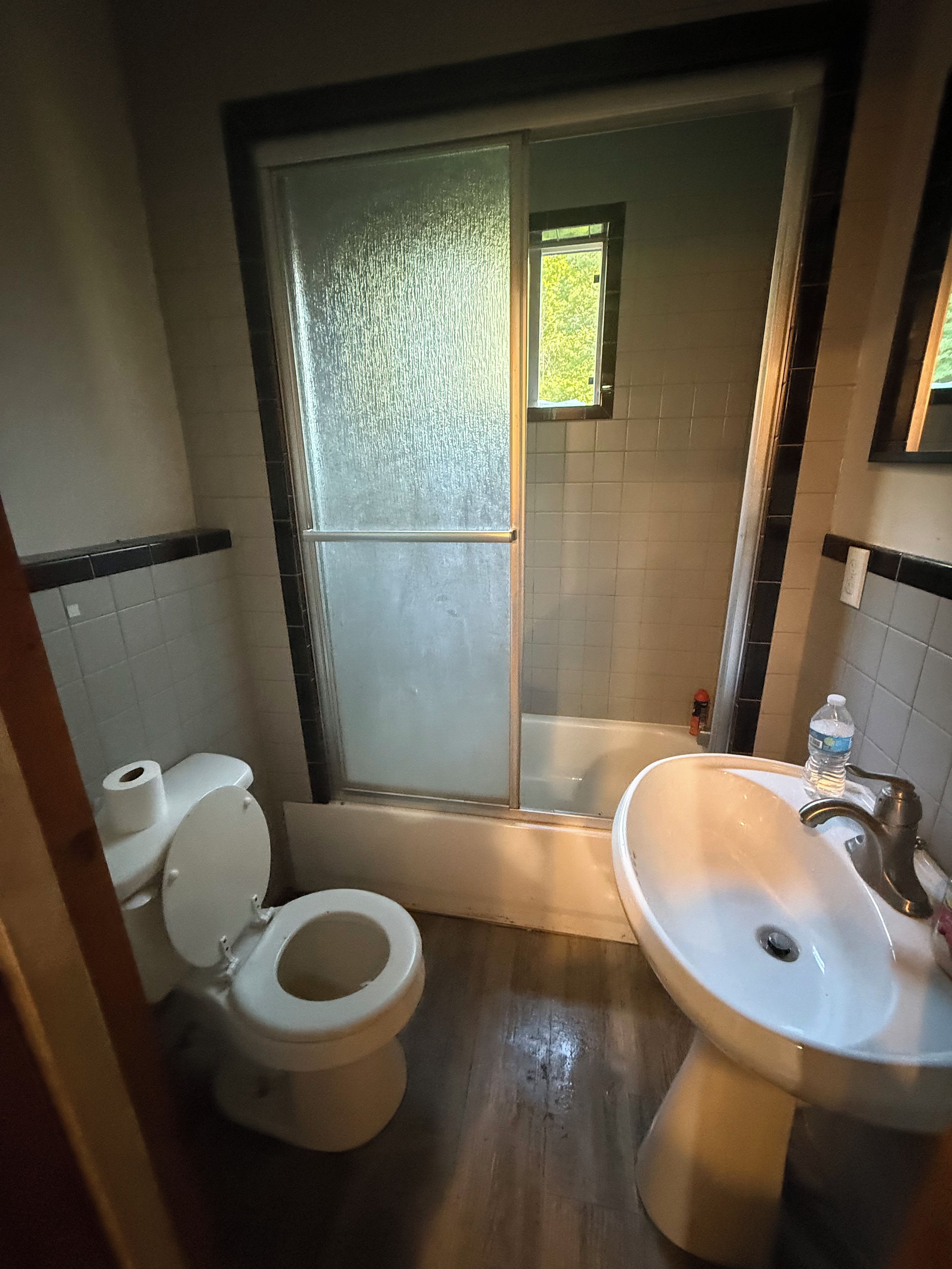 A bathroom with a toilet, a sink, and a shower area.