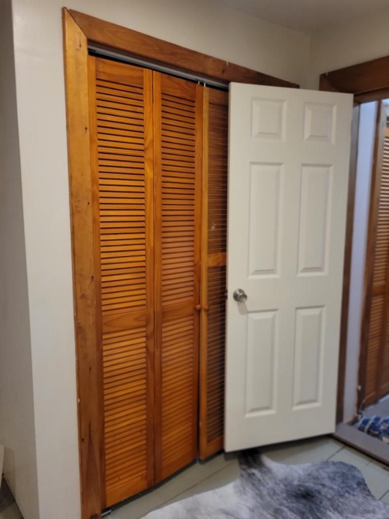 Une pièce avec une armoire en bois, une porte blanche et un tapis à motifs.