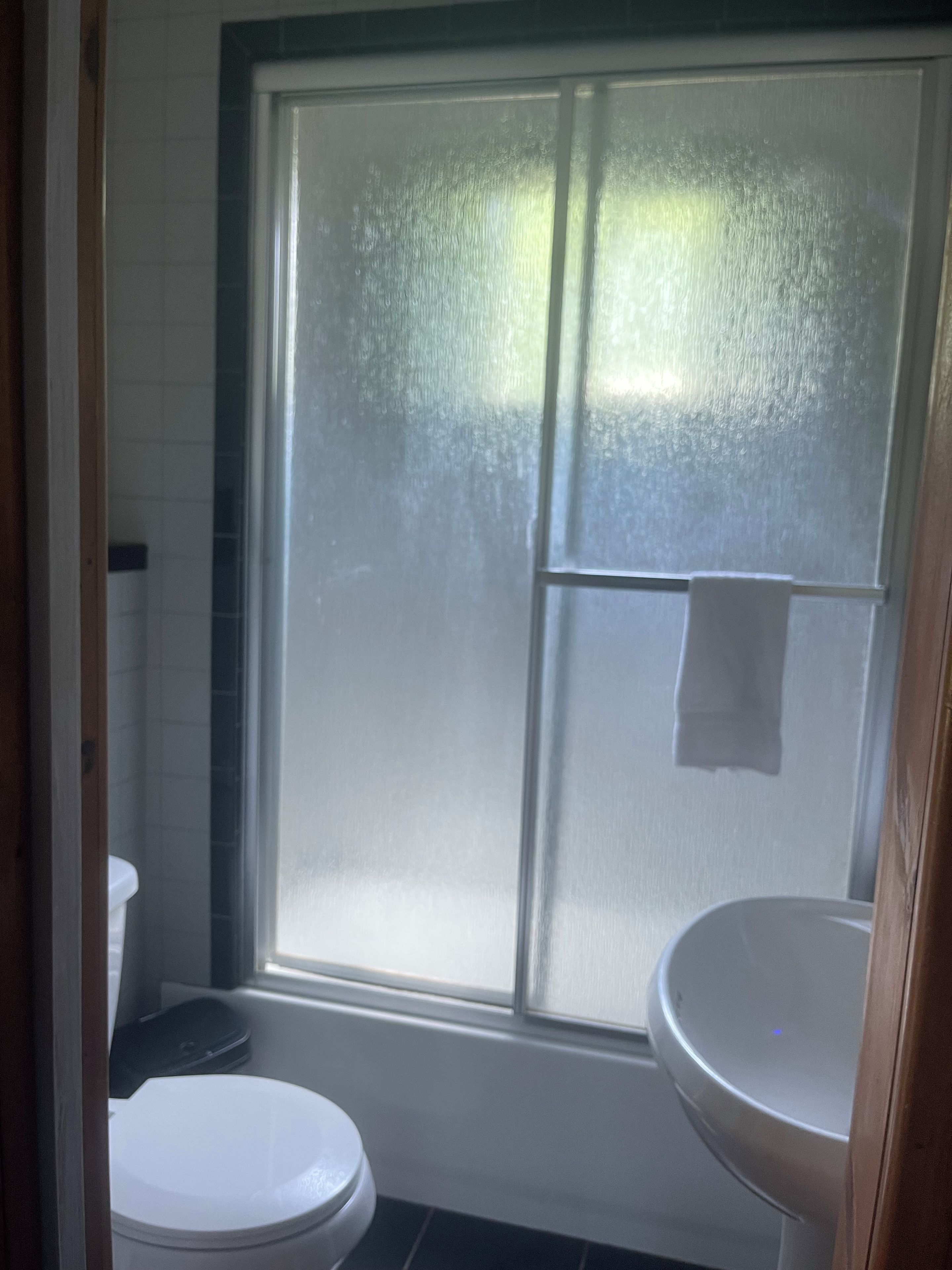 A bathroom with a toilet, a sink, and a window with frosted glass.