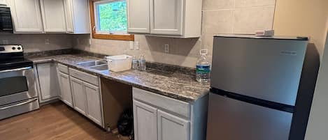 A kitchen with white cabinets, a stainless steel refrigerator, and a granite countertop.