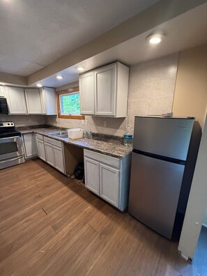 A kitchen with white cabinets, a stainless steel refrigerator, and a granite countertop.