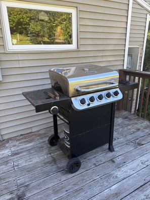 A portable barbecue grill with a lid, a side burner, and a wheelbarrow attachment, placed on a wooden deck. - Historic Farm House & Barn in Quaint Wolcott NY 1 mile from Lake Ontario (Wolcott)