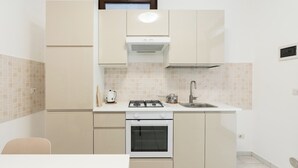 Een compacte keuken met een gasfornuis, oven, spoelbak en een klein aanrecht.