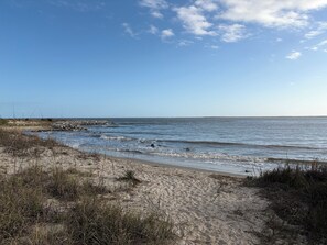 A beach with sand, sparse vegetation, and calm water. - Best sunsets in the Lowcountry! Enjoy views of Bohicket Creek & Seabrook access (Johns Island)