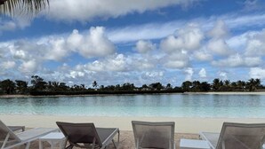 En strand med kristallklart turkost vatten, vit sand och solstolar.