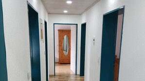 En hall med trägolv, turkosa dörrar och vita väggar.