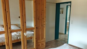 Ett rum med en garderob i trä, en säng med vita sängkläder och ett trägolv.