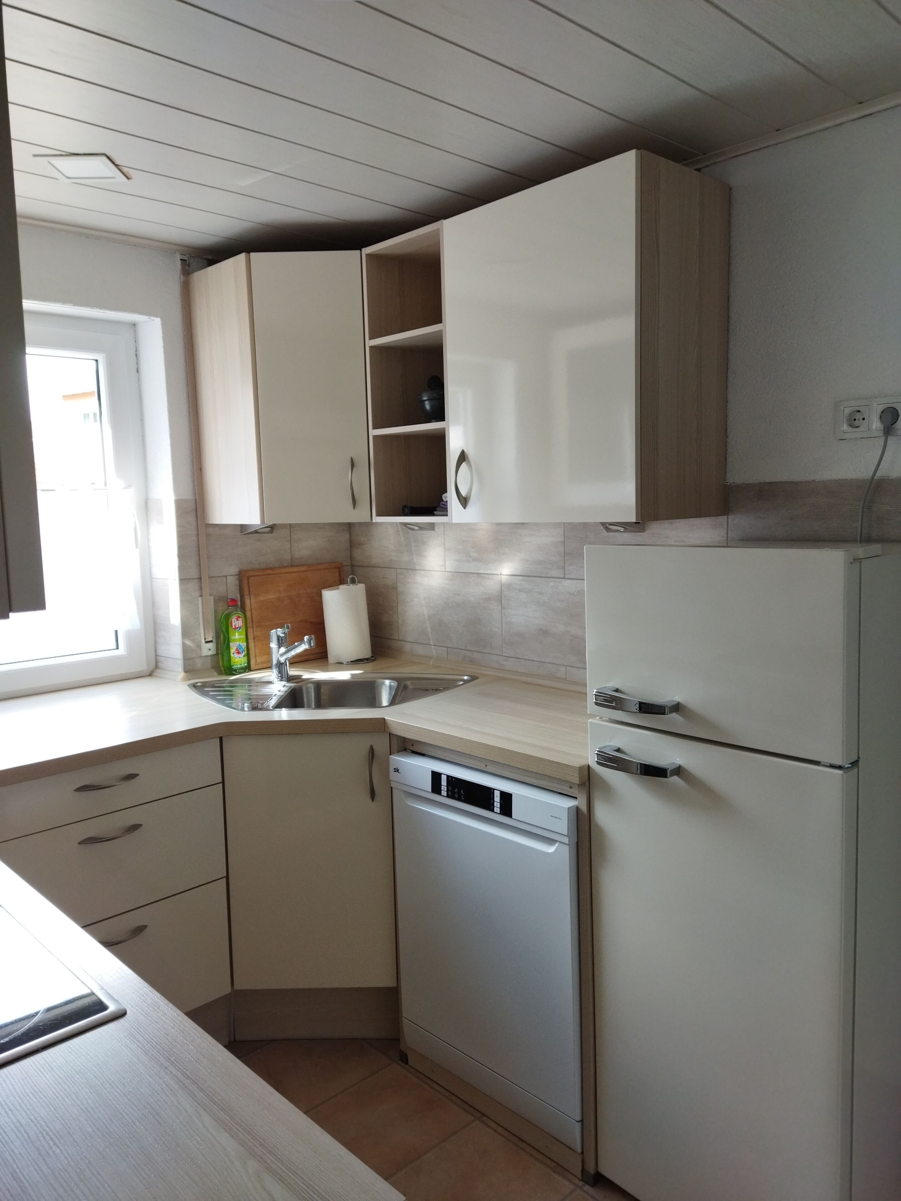 A kitchen with white cabinets, a dishwasher, a sink, and a window.