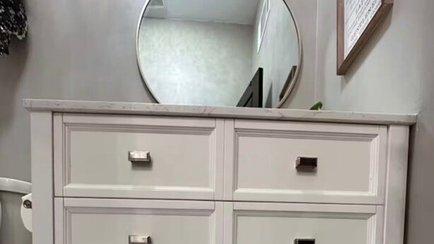 A white vanity with four drawers, a mirror, and a wicker basket underneath. - Historic Downtown Loft in Cartersville (Cartersville)