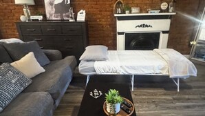 A living room with a brick wall, a sofa, a coffee table with a plant, and a fireplace. - Historic Downtown Loft in Cartersville (Cartersville)