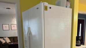 Un refrigerador blanco en una habitación con paredes amarillas y suelo de madera.