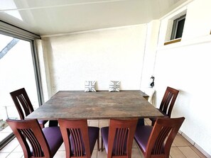 A rectangular dining table with six chairs, a small window, and a door on the wall. - Apartment for 6 people, 50 m from the coastal path and 500 m from Fort-Bloqué beach, Wi-Fi,... (PLOEMEUR)
