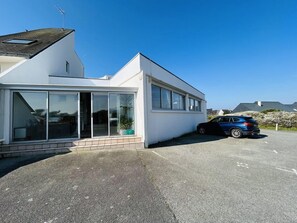 A modern building with large windows, a car parked in front, and a clear blue sky. - Apartment for 6 people, 50 m from the coastal path and 500 m from Fort-Bloqué beach, Wi-Fi,... (PLOEMEUR)