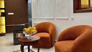 A modern living room with a sofa, a coffee table with fruit, a heater, and decorative wall lights. - Maison de charme en ferme privée- Atlas (El Hajeb)
