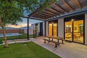 Une maison moderne dotée d’un patio, d’une piscine et offrant une vue sur les montagnes.