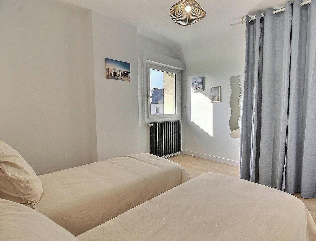 Quarto com duas camas, um radiador, uma janela e vista para o exterior.