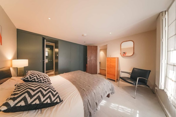 Una camera d'albergo con un letto, una sedia, una scrivania, uno specchio e un armadio.