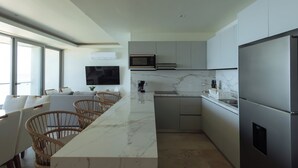 A modern kitchen with a marble countertop, built-in appliances, and wicker chairs.