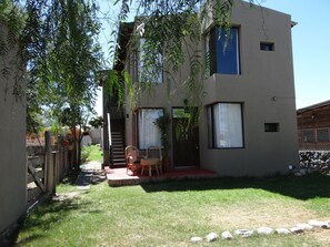 Un bâtiment à deux étages doté d’un patio couvert, d’un escalier et d’un petit espace extérieur aménagé pour s’asseoir.