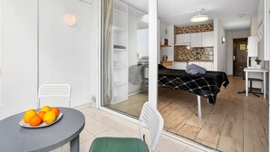 A compact living space with a bed, kitchenette, and a dining area with a table and chairs. - Sea View Studio Playa de Las Americas (Playa de Las Americas)