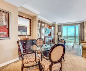 Une chambre d’hôtel comprenant un coin repas, une télévision, une grande fenêtre avec vue et un balcon.