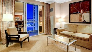 Ein Hotelzimmer mit Sofa, Sessel, Glastisch und einem Bild an der Wand.