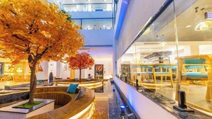 A modern hotel lobby with a central seating area, a glass storefront, and a multi-level ceiling. - 12C Baiyujing Hot Spring Resort Furong (Xiangxi)