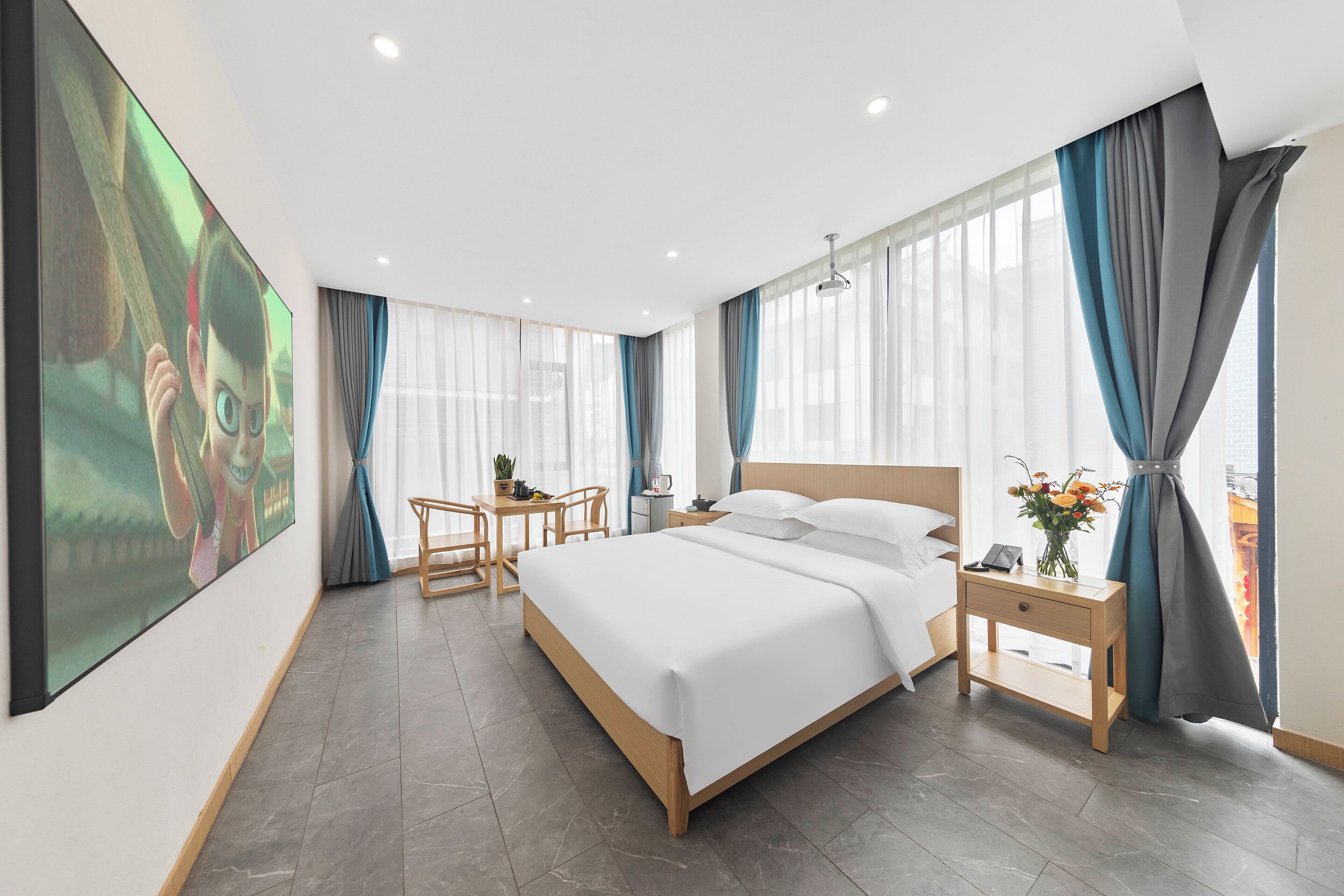 Une chambre d’hôtel moderne avec un grand lit, des tables de chevet, un bureau et une grande fenêtre avec des rideaux.