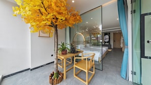 A modern hotel room with a bed, a desk with a chair, a potted plant, and a glass partition. - 12C Baiyujing Hot Spring Resort Furong (Xiangxi)