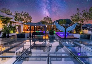A rooftop terrace with a glass floor, a seating area with a view of the night sky, and a large wing-shaped light fixture. - Twelve Cities Mountain View Hot Spring-Pool Holiday Homestay Near Waterfall-English Service-Free Shuttle from Furong Town High-speed Railway Station (Xiangxi)