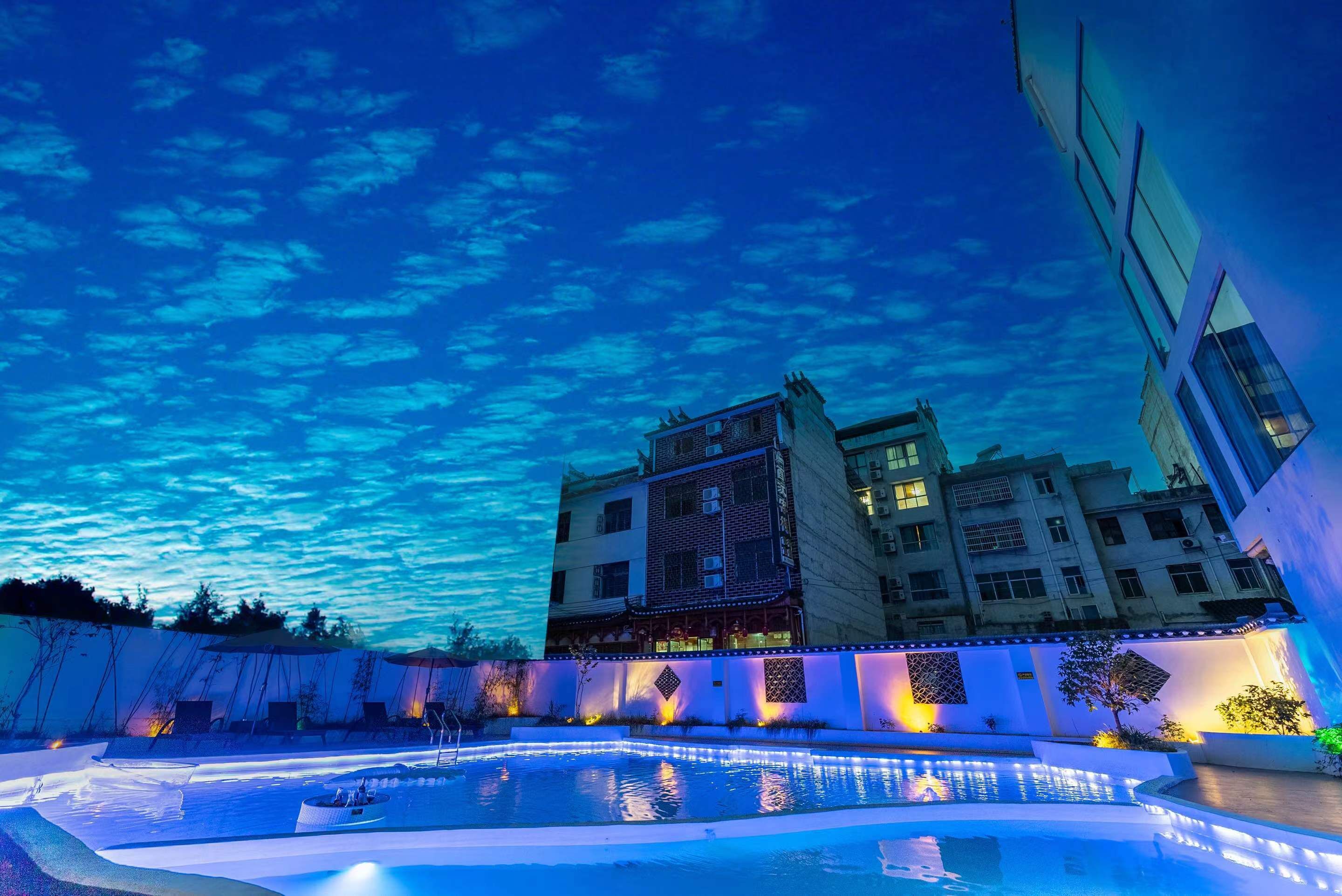 Un hotel con piscina, patio y un edificio de varios pisos y balcones.
