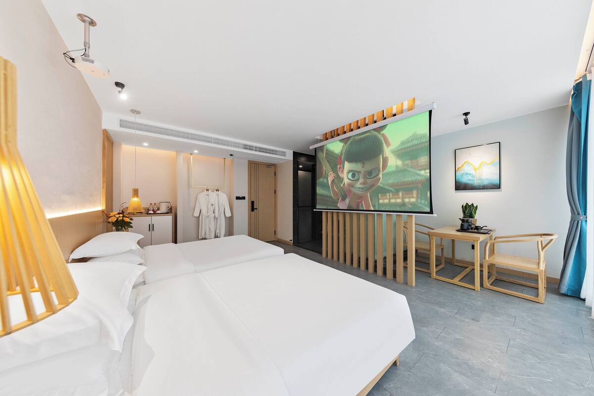 Habitación de hotel con una cama grande, un escritorio con silla, una pantalla de televisión y un estante en la pared.