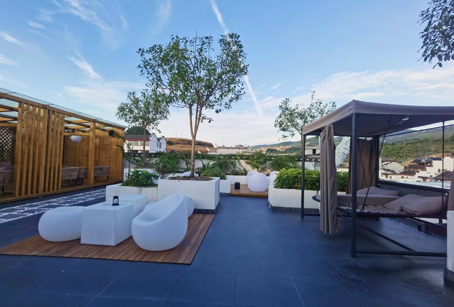 A rooftop terrace with seating areas, a covered seating area, and a view of the surrounding landscape.