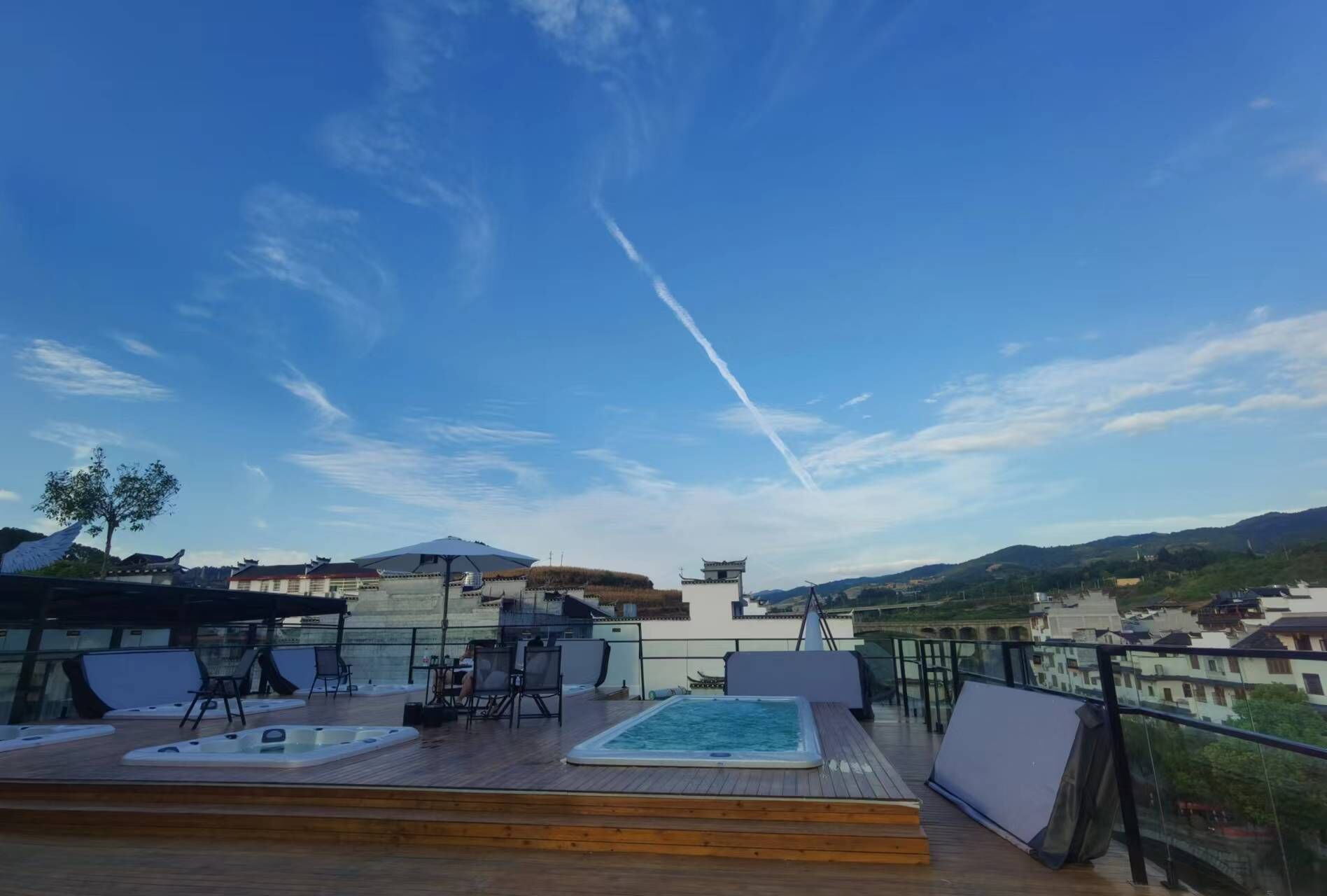 Eine Dachterrasse mit Pool, Sitzgelegenheiten und Blick auf die umliegende Landschaft.