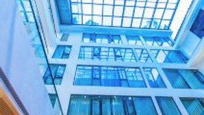 A modern building with a glass atrium and multiple floors. - 12C Baiyujing Hot Spring Resort Furong (Xiangxi)