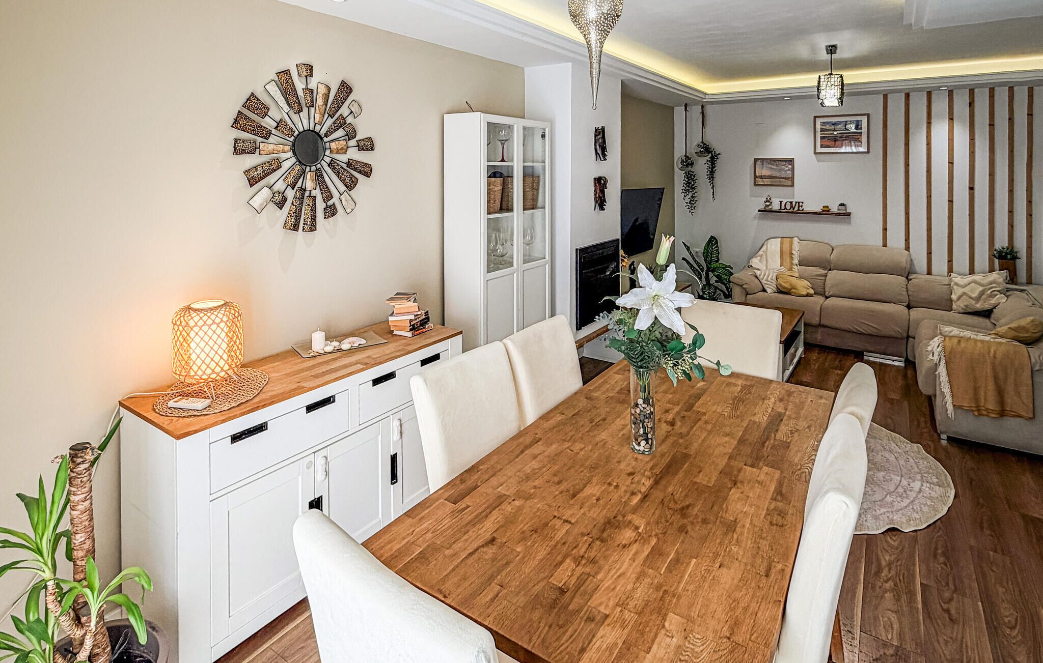 Un coin repas avec une table et des chaises en bois, un meuble blanc et un élément décoratif mural.