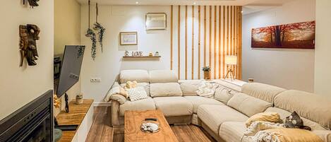 Ein modernes Wohnzimmer mit einem Ecksofa, einem Holztisch und einem Kamin.