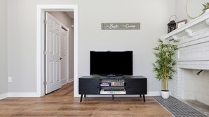 A hallway with a black entertainment unit, a television, and a potted plant. - New Listing! The Landing Pad - 8 minutes to ATL Airport! (Atlanta)